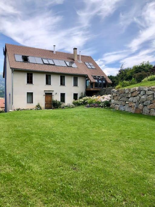 une grande maison blanche avec des fenêtres et une cour verte dans l'établissement Le Presbytère - Des vacances à la montagne, à Saint-Laurent-du-Cros