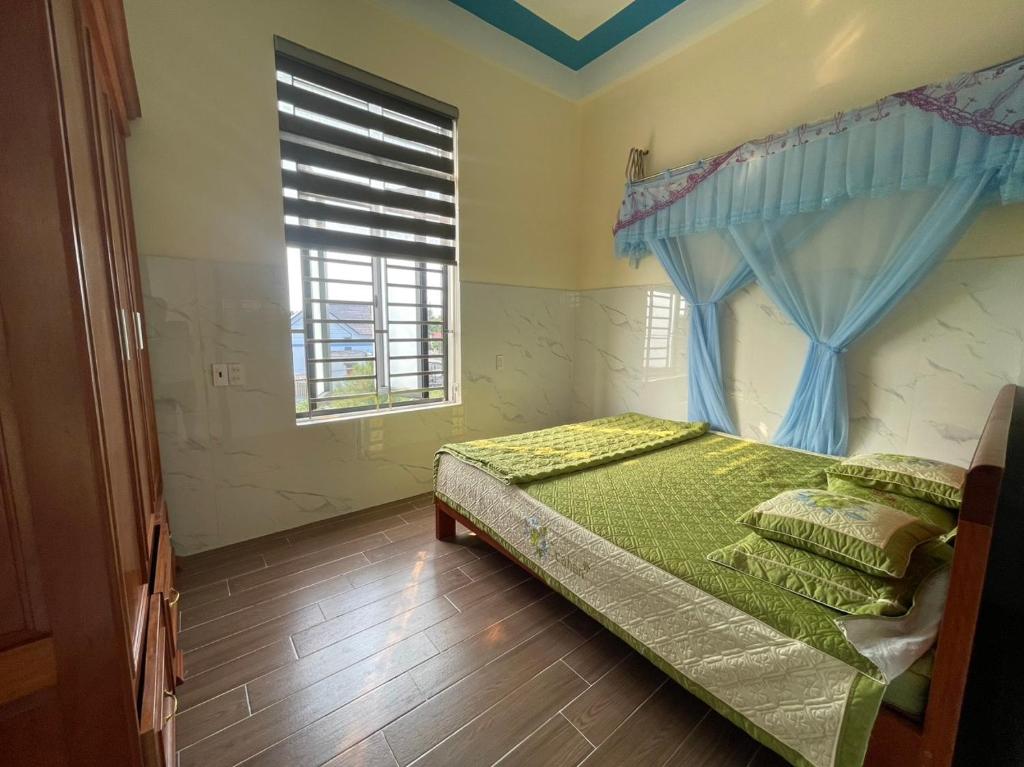ein Schlafzimmer mit einem Bett mit einem blauen Vorhang und einem Fenster in der Unterkunft Homestay Sea View Ông Hoành 
