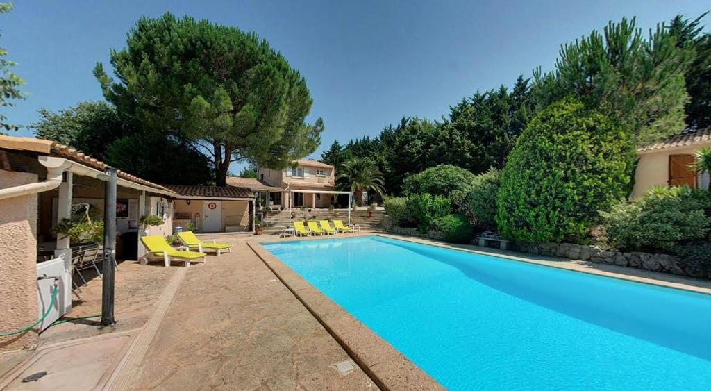 a swimming pool with yellow chairs and a house at Mas des Petits Loups in Cabrières