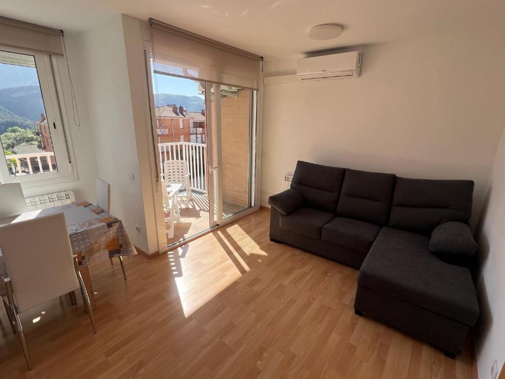 a living room with a couch and a large window at Apartament reformat al Berguedà in Sant Jordi de Cercs