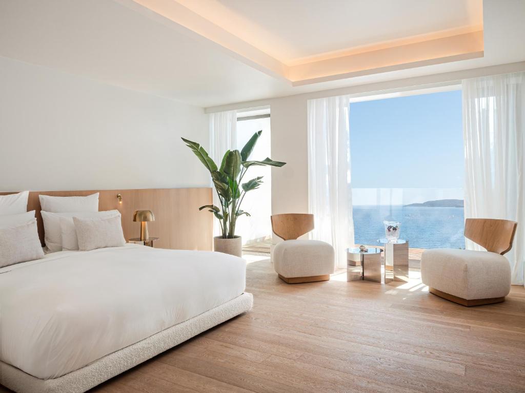 a white bedroom with a bed and a large window at The Roc Club in Athens