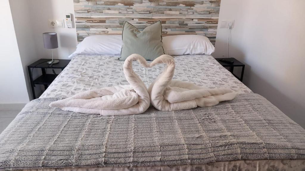two towels shaped like swans are on a bed at Guests House River in Málaga