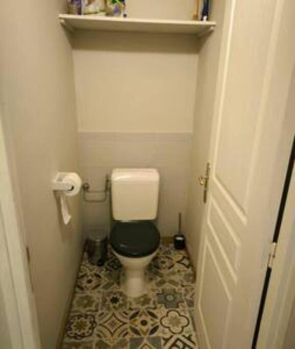 a small bathroom with a toilet with a black seat at 2 pièces au centre-ville in Roquebillière
