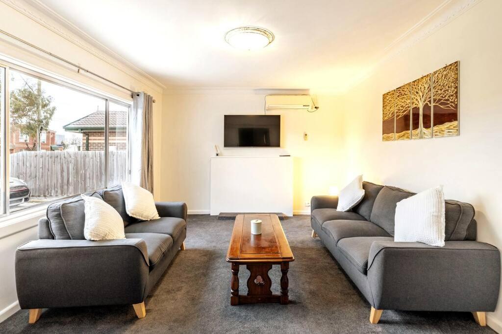 a living room with two couches and a coffee table at Charming Home Near Melbourne Airport & CBD in Melbourne
