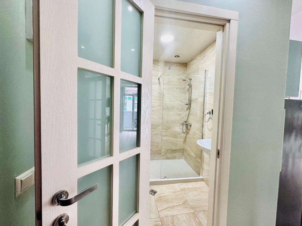 uma casa de banho com um chuveiro e uma porta de vidro em Lina’s seaside apartments em Batumi