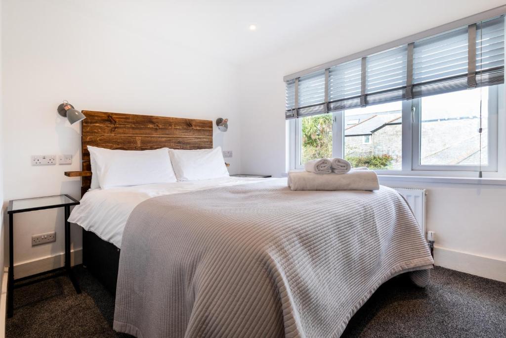 biała sypialnia z dużym łóżkiem i oknem w obiekcie The Nook w St Ives