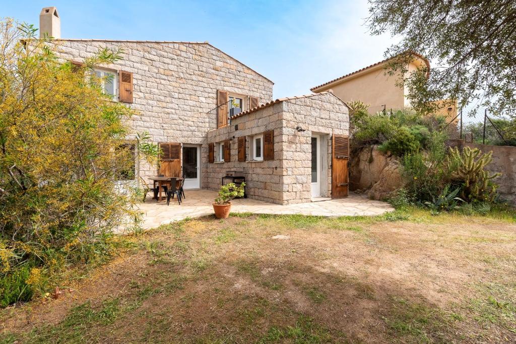 a large brick house with a patio in front of it at Bergerie Piattone - Maison avec grand jardin in Pianottoli-Caldarello