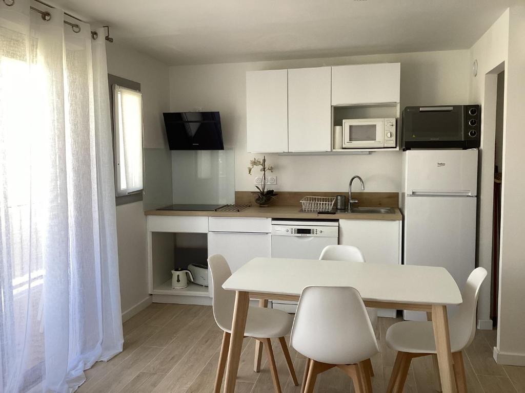 une petite cuisine avec une table et des chaises dans une pièce dans l'établissement Les Embruns Appart 1ere ligne Carnon parking gratuit, à Mauguio