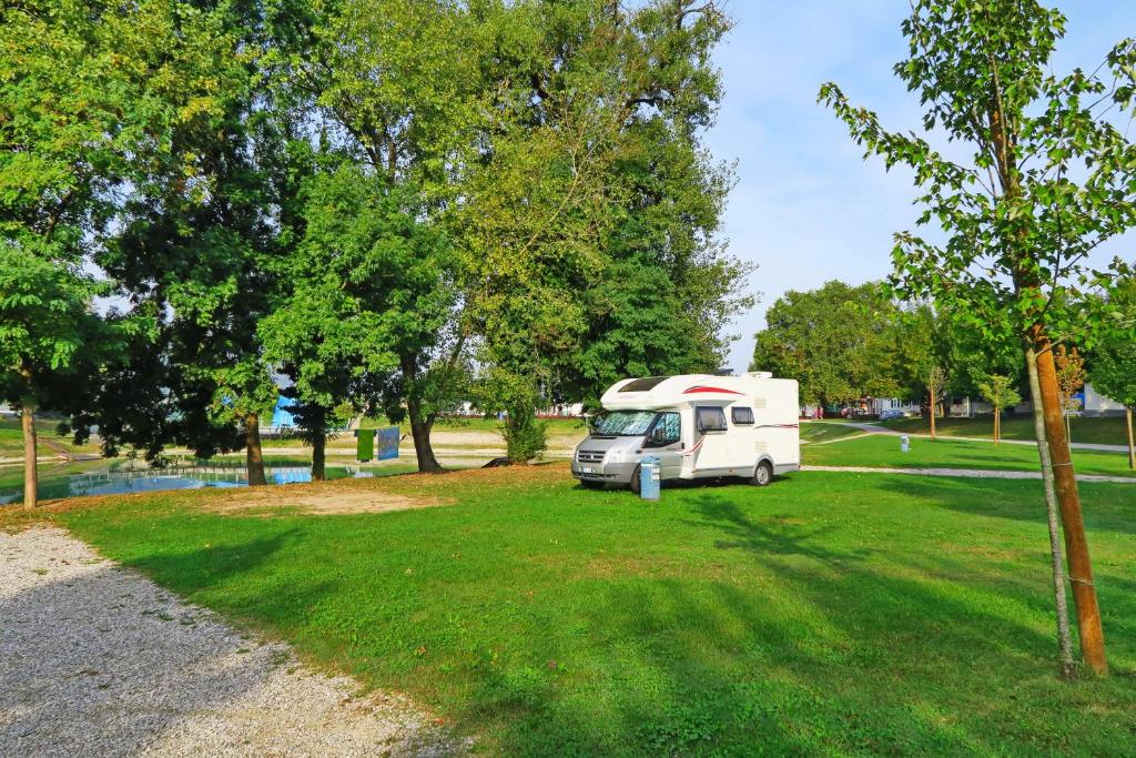 una caravana blanca estacionada en un parque con árboles en Camp Terme Čatež en Čatež ob Savi