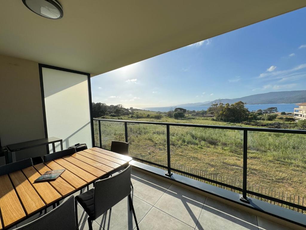Cette chambre dispose d'une table et d'un balcon avec vue. dans l'établissement BEL'ORIZONTE Proche centre ville et plage, vue mer, à Propriano