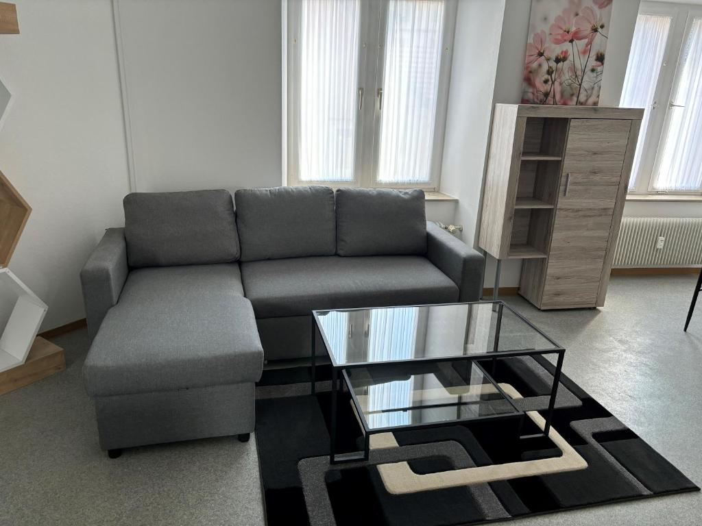 ein Wohnzimmer mit einem Sofa und einem Glastisch in der Unterkunft Henneberger Hof in Münnerstadt