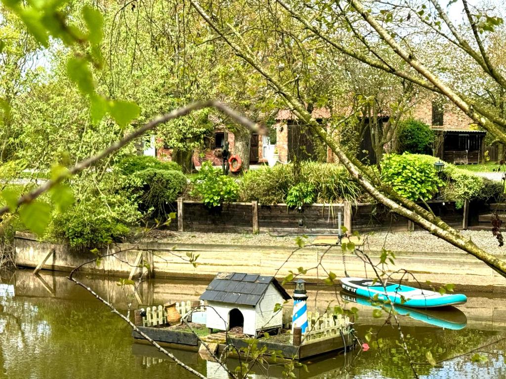 a small house and a boat in the water at 18th century 3 bed Barn- Beautifully converted in Lincolnshire