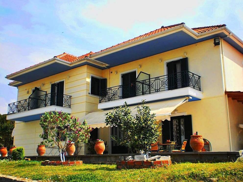 a large yellow house with vases in front of it at Guesthouse Bizani in Neo Mpizani