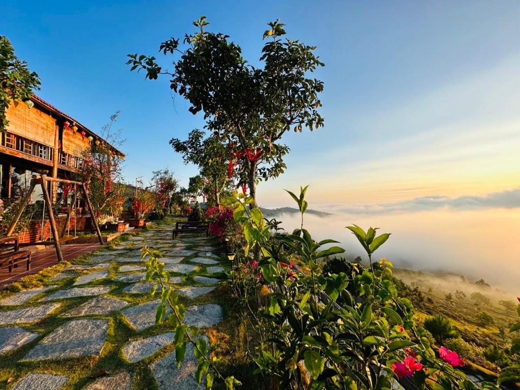 un camino de piedra con árboles y flores en una montaña nebulosa en Nhà gỗ Homestay, en Bao Loc