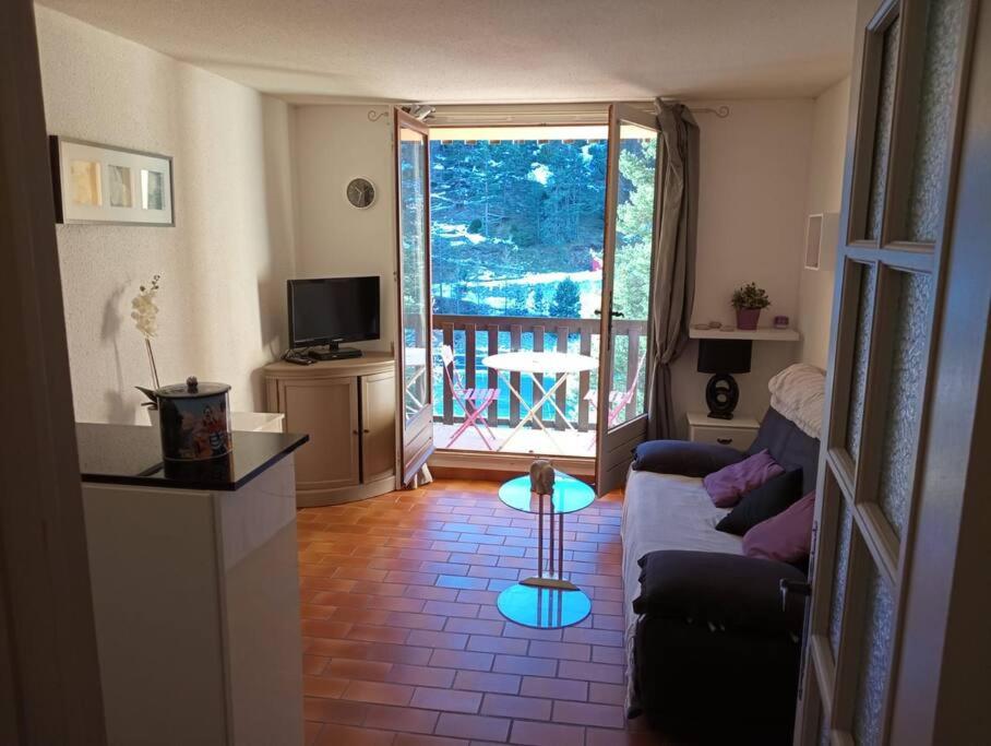 sala de estar con sofá y balcón en Studio proche activité en Saint-Martin-Vésubie