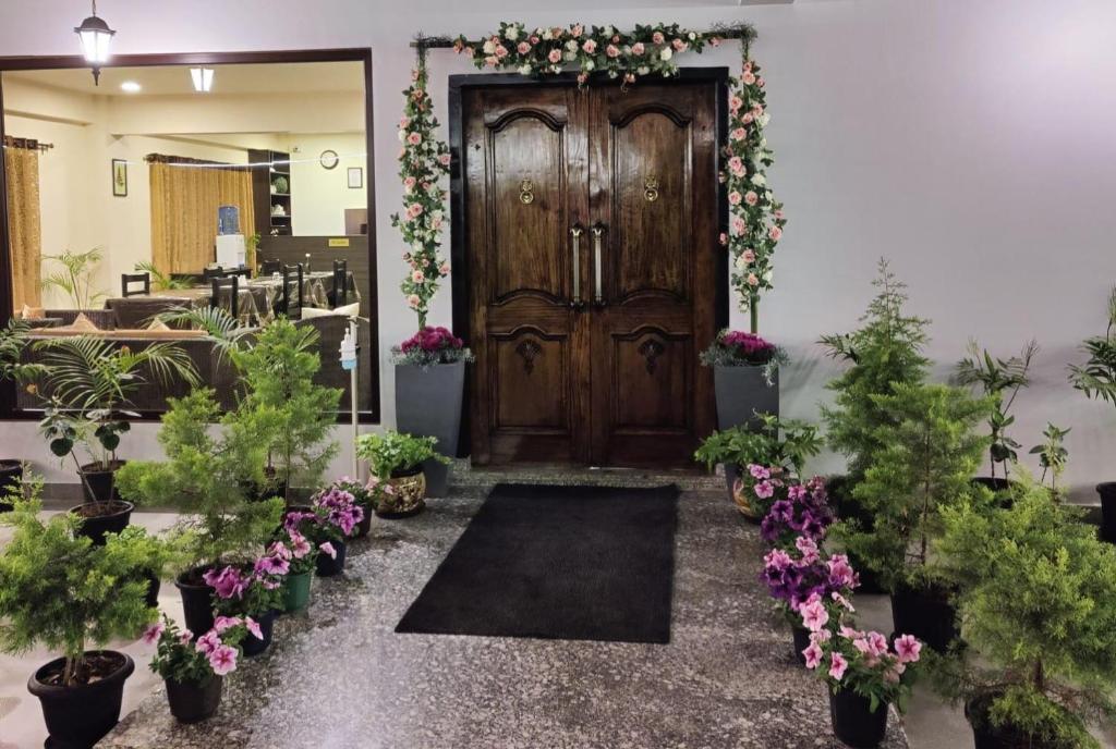 eine große Holztür mit Pflanzen und Blumen in der Unterkunft The Arbour Inn in Shillong
