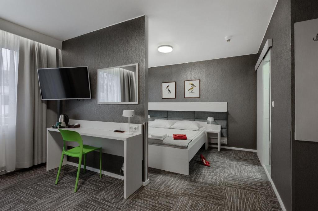 a bedroom with a bed and a desk and a computer at Jantar Resort in Szczecin