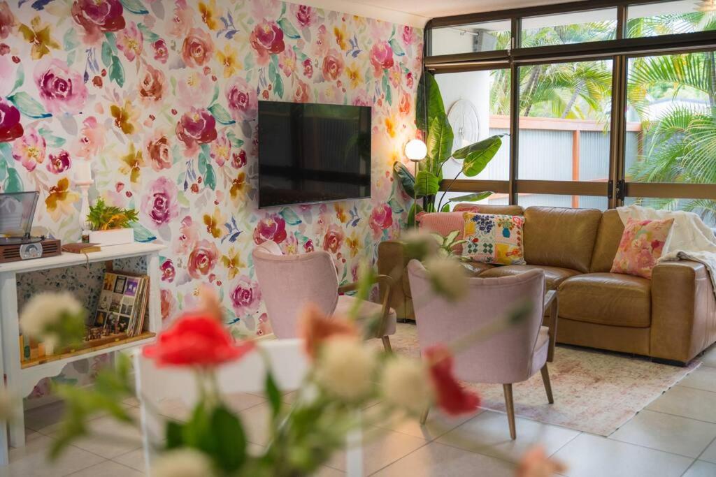 un soggiorno con divano e carta da parati floreale di Palms on Patti Apartment a Rockhampton