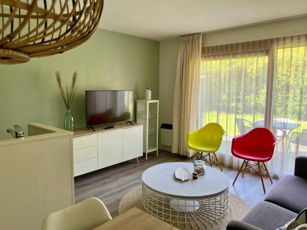 a living room with a tv and some chairs at Appartement Noflik, Amelander Kaap in Hollum