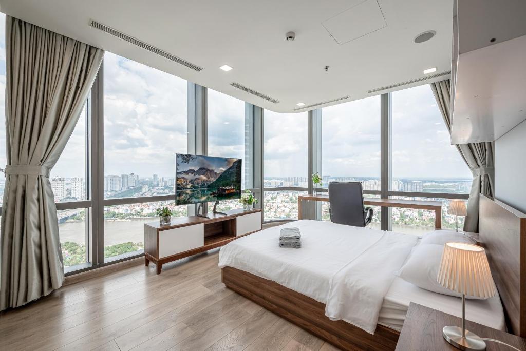 a bedroom with a bed and a tv and windows at THE LANDMARK 81 RESIDENCE LUXURY SUITE in Ho Chi Minh City