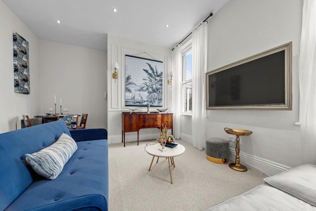 sala de estar con sofá azul y TV de pantalla plana en Pelican Suite - Design 1Bed Flat en Harrogate