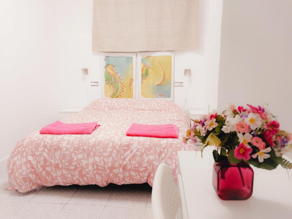 um quarto com uma cama e um vaso de flores em Alojamiento San Juan en Murcia Centro em Múrcia