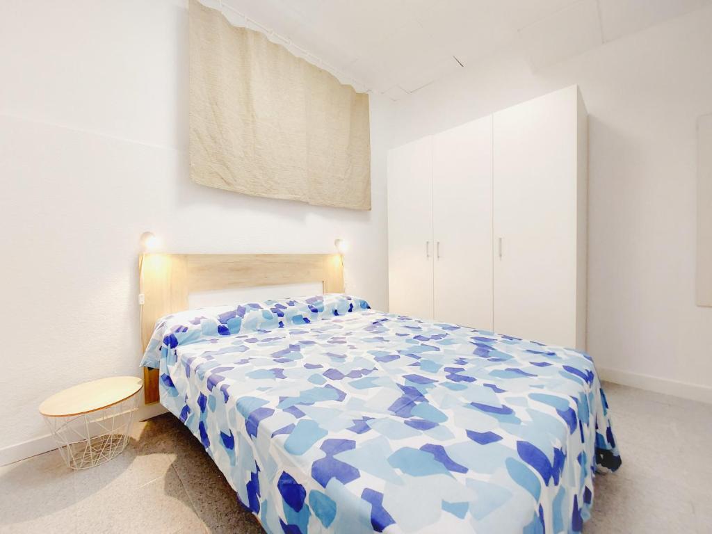 ein Schlafzimmer mit einer blauen und weißen Bettdecke auf einem Bett in der Unterkunft Alojamiento San Juan en Murcia Centro in Murcia
