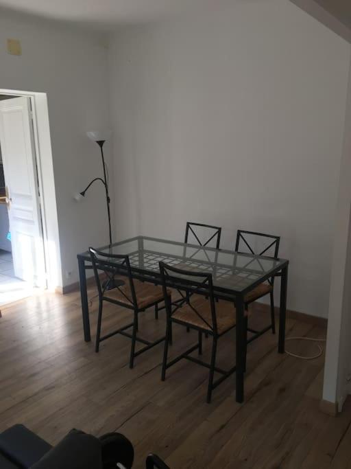 une table en verre avec quatre chaises et une lampe dans une pièce dans l'établissement Maison 6-8 personnes à 15 minutes de Paris, à Sannois