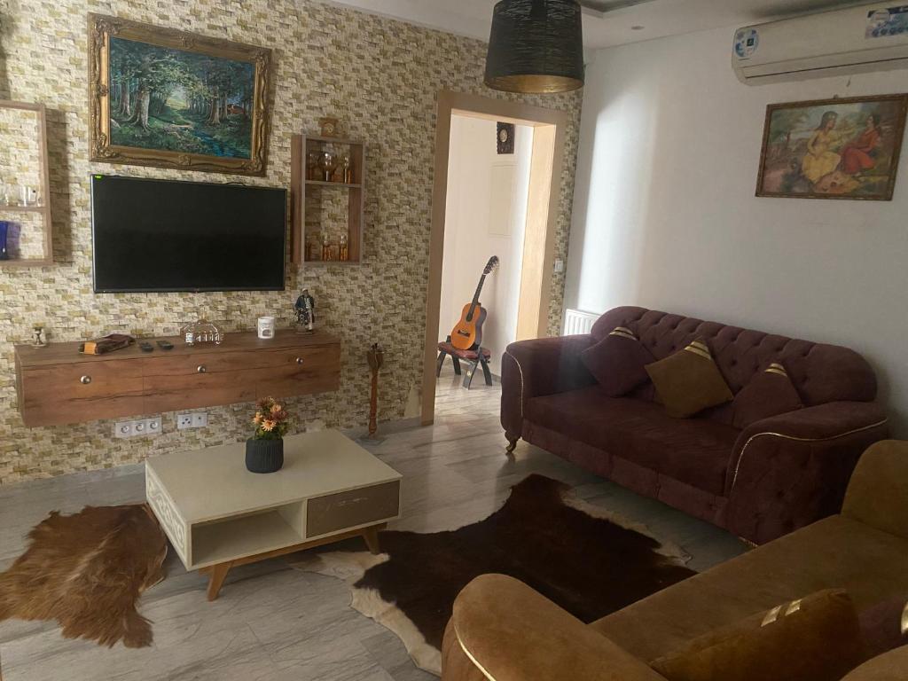 a living room with a couch and a tv at Superbe appartement sahloul 4 in Sousse