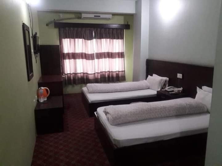 ein Hotelzimmer mit 2 Betten und einem Fenster in der Unterkunft Old Everest Hotel in Khanchikot