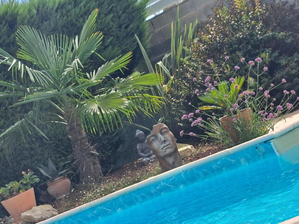 a garden with a statue next to a swimming pool at La Tropézienne in Castéra-Verduzan