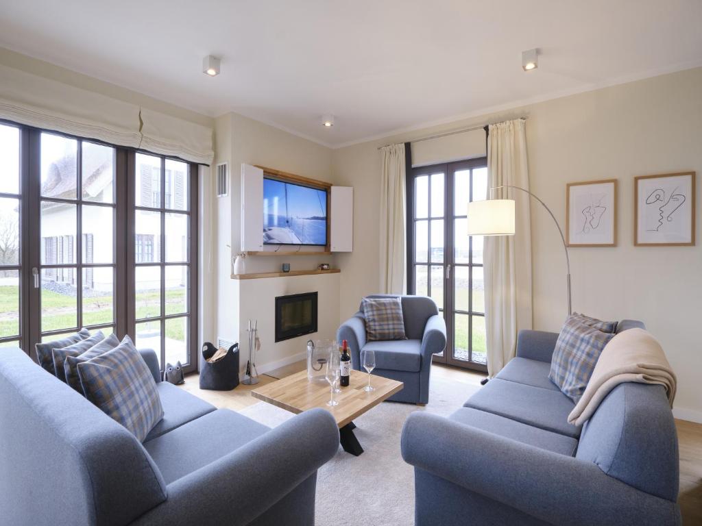 a living room with two blue couches and a tv at Reetland am Meer - Luxus Reetdachvilla mit 3 Schlafzimmern, Sauna und Kamin H07 in Dranske