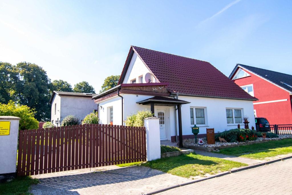 a white and red house with a wooden fence at Ferienhaus Geli 4 in Kröslin