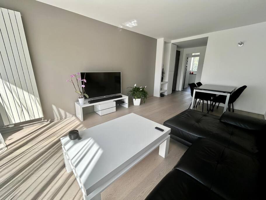 ein Wohnzimmer mit einem schwarzen Sofa und einem weißen Tisch in der Unterkunft Appartement moderne et lumineux in Charenton-le-Pont