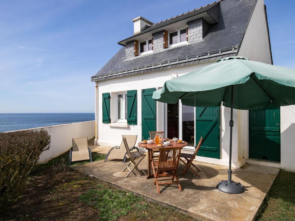 stół z zielonym parasolem przed domem w obiekcie Holiday Home Les Roches - LPU 103 by Interhome w mieście Clohars-Carnoët