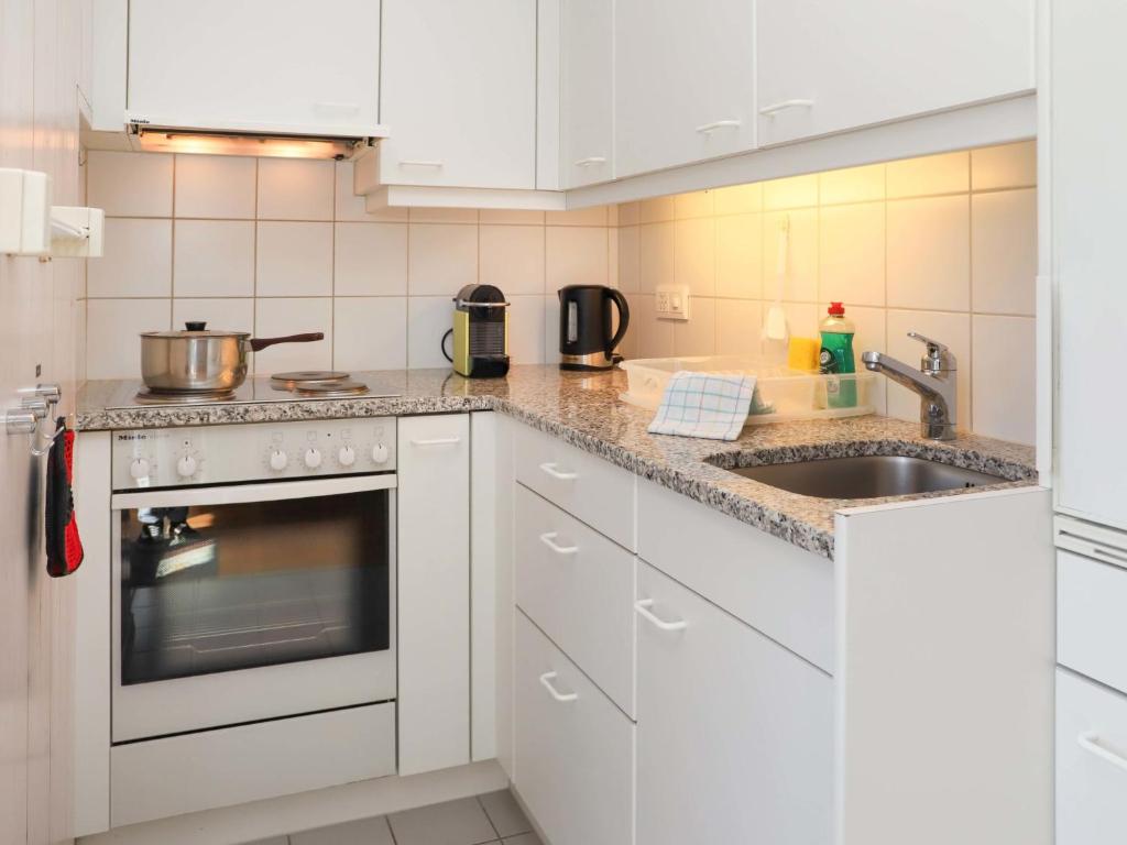 una cucina con mobili bianchi e un lavello di Apartment Monique Nr- 9 by Interhome a Gstaad