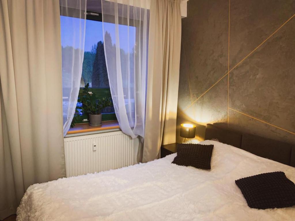 a bedroom with a white bed and a window at Stylowy Apartament w Serocku in Serock