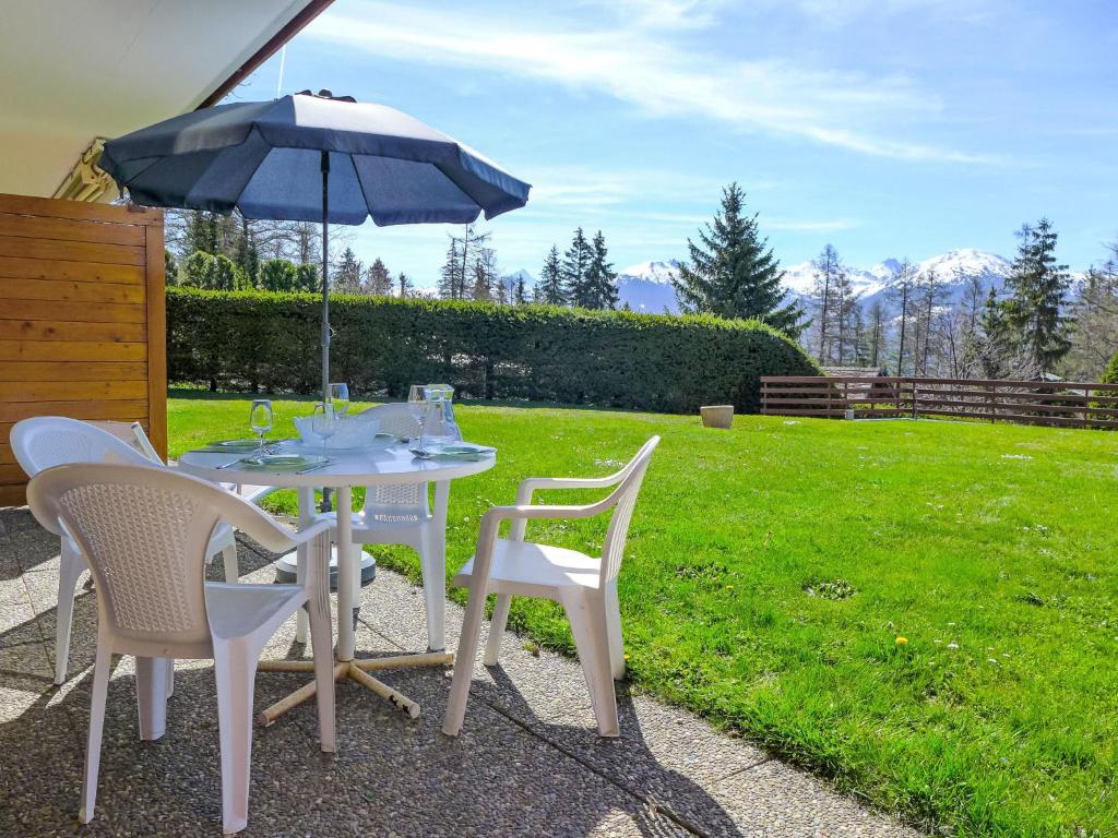 a table and chairs with an umbrella on a lawn at Apartment Santa Barbara by Interhome in Crans-Montana