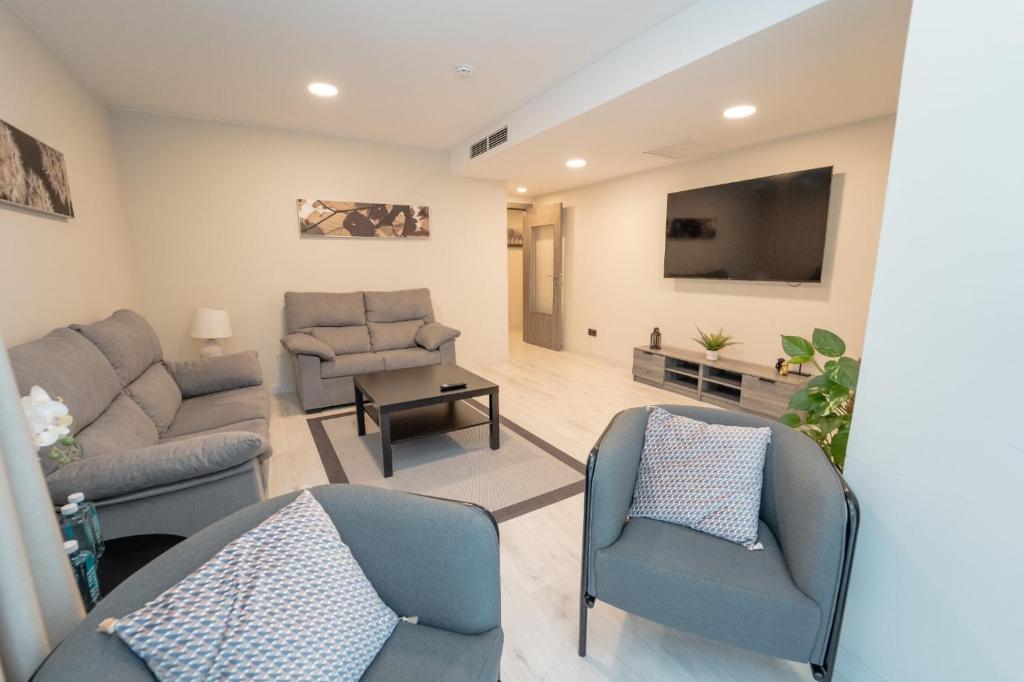 uma sala de estar com um sofá e cadeiras e uma televisão em Lux Apartment em Melide