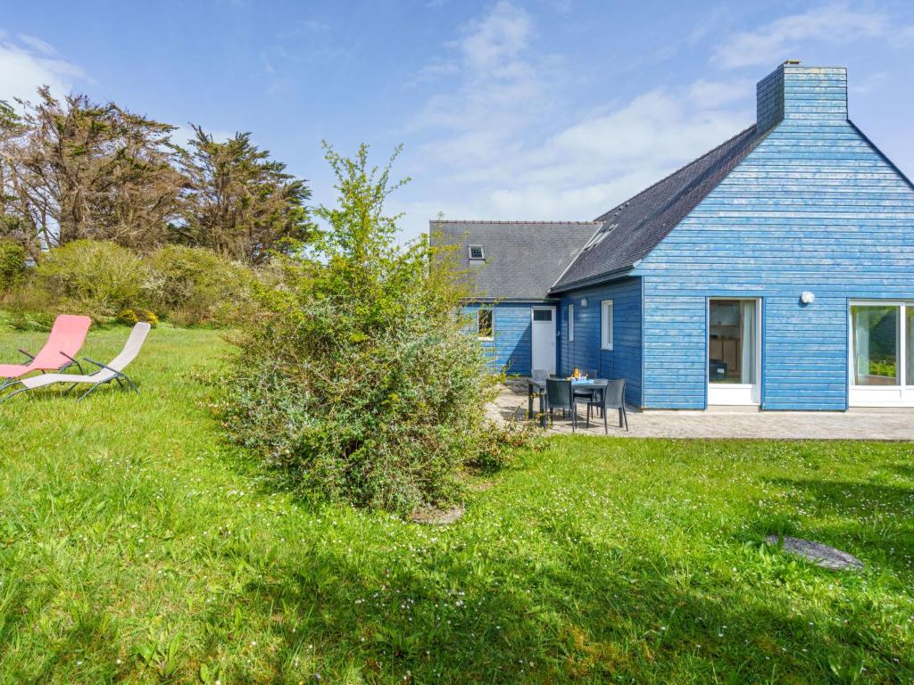 uma casa azul com uma mesa e cadeiras na relva em Holiday Home Maison bleue by Interhome em Kernalléguen