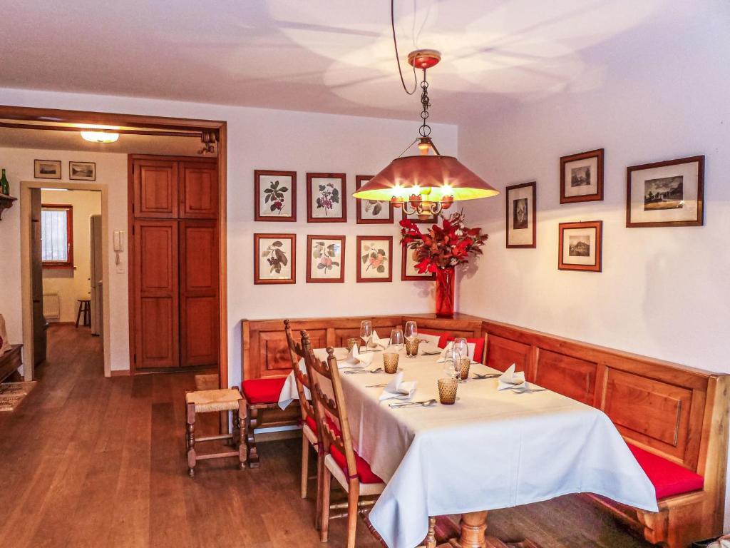 uma sala de jantar com uma mesa longa e um lustre em Apartment Chesa Arlas E2 by Interhome em St. Moritz