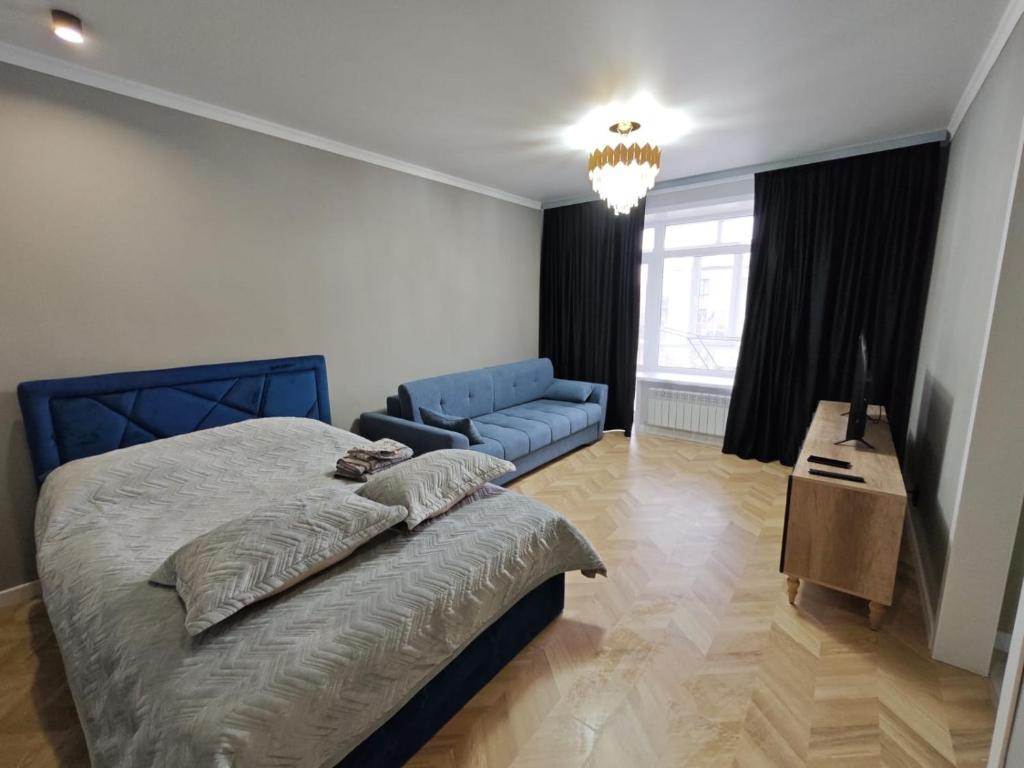 a bedroom with a blue bed and a blue couch at Квартира посуточно in Kokshetau