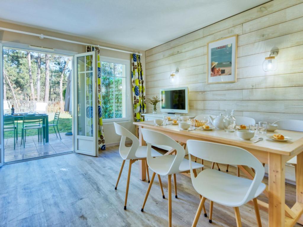 comedor con mesa de madera y sillas blancas en Holiday Home Domaine Golf Resort-2 by Interhome, en Lacanau-Océan