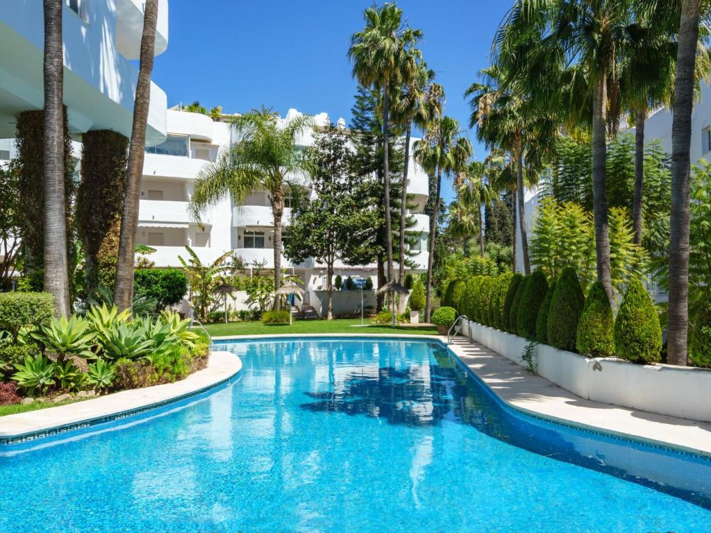 a swimming pool with palm trees and a building at Apartment Marbella Real by Interhome in Marbella