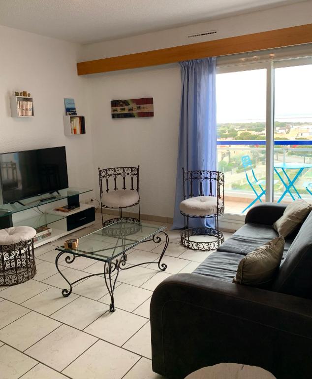 un salon avec un canapé, des chaises et une télévision dans l'établissement Appartement moderne, mer à 50m, au Barcarès