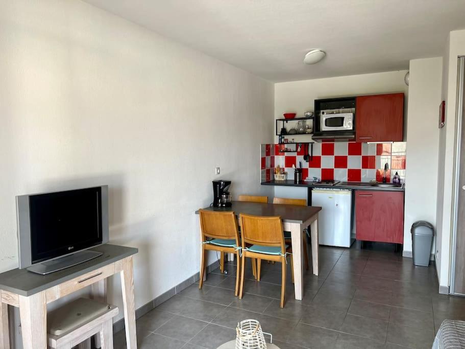 a kitchen with a table and chairs and a television at San José in Juvignac