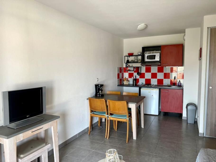 a kitchen with a table and chairs and a kitchen with red and white at San José in Juvignac