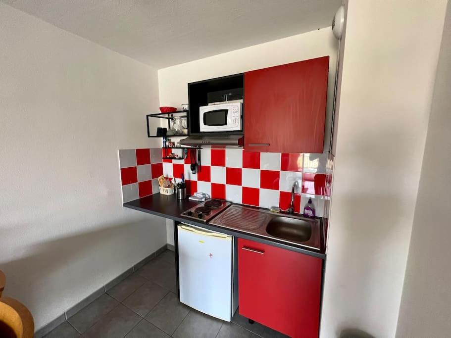 a small kitchen with red and white checkered walls at San José in Juvignac
