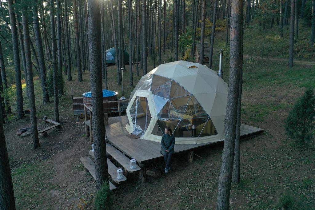 un homme debout devant une tente dans les bois dans l'établissement Asalnai Campsite, à Ignalina