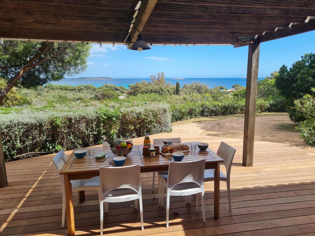 a wooden table and chairs on a deck with the ocean at Holiday Home La Girelle by Interhome in Porto-Vecchio